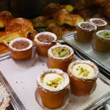 Pâtisseries variées, dont des croissants dorés et des petits gâteaux garnis de crème au chocolat, de pistache ou de crème pâtissière, dans un restaurant florentin.