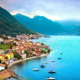 Village coloré au bord d'un lac bleu vif, niché au pied de montagnes verdoyantes. Un paysage typique des 3 lacs en Italie.