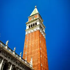 Le campanile de Venise se dresse fièrement sous un ciel bleu éclatant, orné de statues sur son flanc.