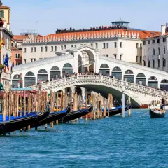 Gondoles amarrées près du célèbre Ponte di Rialto, avec des touristes admirant la vue sur le Grand Canal.