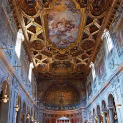 Intérieur de la basilique San Clemente à Rome, avec son plafond doré orné de fresques et ses arcs majestueux.