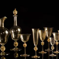 Service en verre doré, digne d'un musée du verre à Venise, avec carafe et verres aux pieds sculptés.