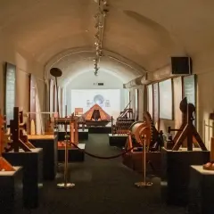 Maquettes d'inventions de Léonard de Vinci exposées dans un couloir voûté, une invitation à explorer le musée Léonard de Vinci à Rome.