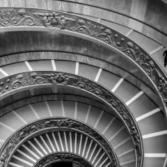 Un escalier en colimaçon orné, rappelant une coupole du Vatican, avec une personne solitaire descendant ses marches.