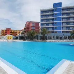 Vaste piscine bleue devant des bâtiments colorés et un grand gonflable de Bob l'éponge, au village ai pozzi.
