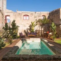 Cour intérieure d'une masseria en Italie, avec piscine, mobilier de jardin et végétation luxuriante.