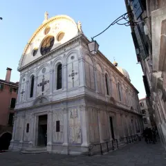 La façade en marbre de Santa Maria dei Miracoli à Venise, ornée d'une grande rosace et d'une croix.