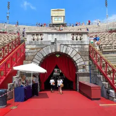 L'Arène de Vérone, avec ses gradins de pierre et ses escaliers rouges, accueille des visiteurs sous un ciel bleu.