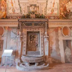 Intérieur de la Villa d'Este : une fontaine ornée de sculptures et de fresques murales dépeignant des scènes mythologiques et des paysages.