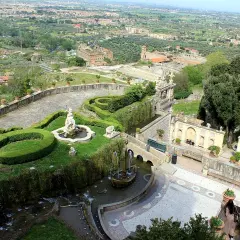 Vue panoramique de la Villa d'Este, avec ses jardins en terrasse, ses fontaines et sa statue, dominant la campagne environnante.