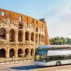 Un bus touristique passe devant le Colisée. Une carte du métro de Rome serait utile pour naviguer dans cette ville historique.