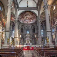 Intérieur de San Zaccaria à Venise, avec des fresques grandioses, des colonnes imposantes et des bancs en bois.