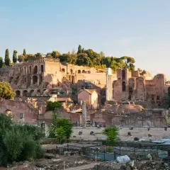Ruines antiques sur le mont Palatin à Rome, baignées par la lumière dorée du soleil. Des colonnes brisées et des murs de briques témoignent de la grandeur passée.