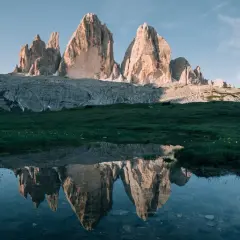 Les Trois Cimes de Lavaredo se reflètent dans un étang près de Misurina, sous un ciel bleu clair.