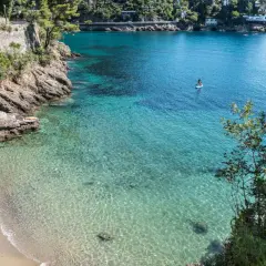 Un homme profite de ses vacances à Portofino, se baignant dans les eaux cristallines. Une personne fait du paddleboard au loin.