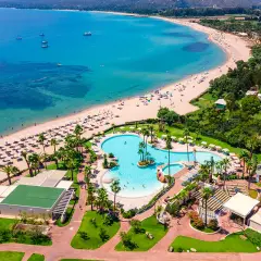 Vue aérienne du **hôtel club Saraceno** avec sa plage de sable fin, sa mer turquoise et sa piscine spectaculaire.
