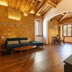 Salon de la villa Mazzanta avec murs en briques apparentes, poutres au plafond, canapé confortable et table à manger.