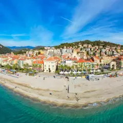 Vue panoramique de la plage et de la ville colorée de Finale Ligure, Italie, sous un ciel bleu éclatant.