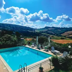 Piscine étincelante devant une **ferme toscane** pittoresque, avec des collines ondulantes et un ciel bleu éclatant.