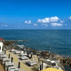 Plage aménagée à San Bartolomeo al Mare, avec chaises longues et parasols face à la mer bleue sous un ciel d'été.