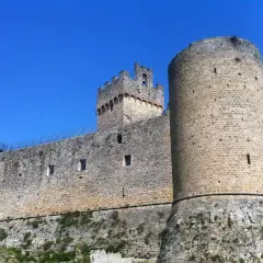 Château médiéval imposant à Poggibonsi, Italie, avec ses tours rondes et carrées sous un ciel bleu éclatant.