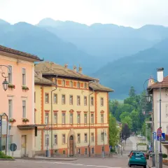Vue d'une rue à Cavalese, Italie, avec des bâtiments colorés et des montagnes en arrière-plan.