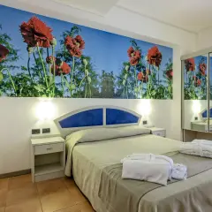 Chambre d'hôtel Antares Sicile avec fresque de coquelicots rouges. Peignoirs blancs et chaussons prêts pour les clients.