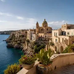 Vue d'une ville côtière italienne perchée sur une falaise, avec des maisons blanches et une église. Idéal pour une maison à louer en Italie.