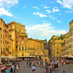 Place animée de Campo de' Fiori à Rome, avec des terrasses de café, des bâtiments colorés et une statue au centre.