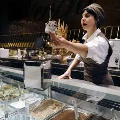 Une vendeuse présente une coupe de glace artisanale, un délice typique de Rome.