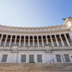 Majestueux monument à Victor-Emmanuel II à Rome, avec ses colonnes imposantes et ses sculptures, sous un ciel bleu clair.