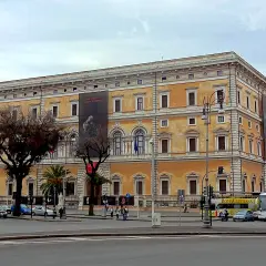Le **Palazzo Massimo alle Terme**, un édifice majestueux, se dresse fièrement, orné d'une bannière publicitaire.