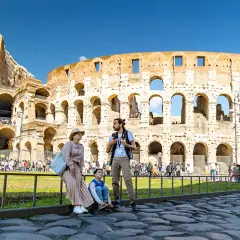 Famille admirant l'imposante arène de Rome, le Colisée, sous un ciel bleu éclatant.