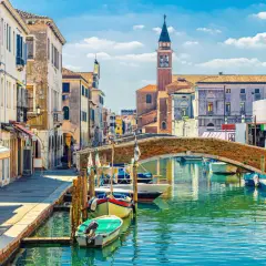 Un rêve d'aller à Venise : un canal bordé de maisons anciennes, un pont de briques et des gondoles.
