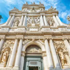 Façade baroque de Santa Maria del Giglio à Venise, ornée de statues et de colonnes imposantes sous un ciel bleu.