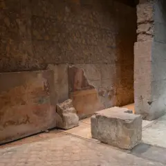 Vestiges d'une fresque murale dans la maison d'Auguste à Rome, avec des blocs de pierre et des murs en ruine.