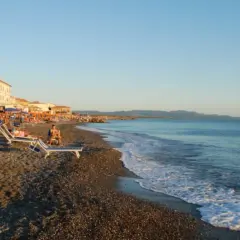 Plage de Cecina, Italie. Chaises longues et parasols sur le sable, mer calme sous un ciel bleu.