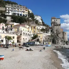 Vue pittoresque de Cetara, Italie, avec ses maisons colorées accrochées à flanc de colline et sa tour médiévale surplombant la mer.