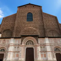 Façade imposante de la basilique San Petronio, mélange de briques rouges et de marbre blanc, sous un ciel bleu.