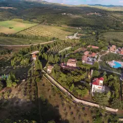 Vue aérienne du Pian dei Mucini, un domaine toscan avec des villas, des cyprès et une piscine.
