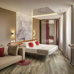 Chambre moderne avec un lit, un canapé et une œuvre d'art murale inspirée de Michel-Ange, typique du **hotel Regno Rome**.
