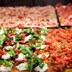 Des pizzas romaines rectangulaires appétissantes, dont une à la mozzarella fraîche, olives et roquette, la meilleure pizza Rome.