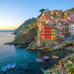 Village vacances La Spezia : maisons colorées accrochées à la falaise, bateaux dans le port, mer bleue.
