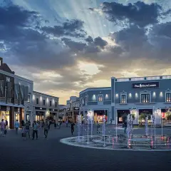 Un soir à l'outlet Sicile, les fontaines illuminées dansent sous un ciel dramatique, devant les boutiques Gucci et Polo Ralph Lauren.