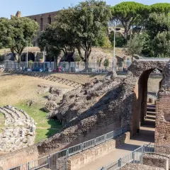 Ruines antiques du Circo Massimo à Rome, avec des gradins en pierre et une arche de briques menant à des escaliers.