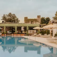 Piscine d'un hôtel club sur la côte amalfitaine, avec des chaises longues, des parasols et un bar extérieur.