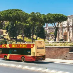 Un bus touristique rouge et jaune circule près de l'Arc de Constantin. Le Vatican n'est pas loin, offrant une vue sur Rome.
