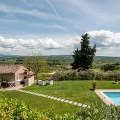 Magnifique vue sur des gîtes en Toscane avec piscine, jardin verdoyant et paysage vallonné sous un ciel bleu.