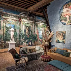 Intérieur du museo Fortuny, avec une statue antique, des peintures murales luxuriantes et des meubles confortables.