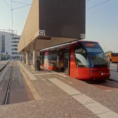 Un tram rouge moderne à Venise, prêt à partir. D'autres bus sont garés à proximité, attendant les passagers.